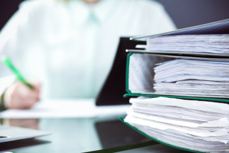 Bookkeeper or financial inspector making report, calculating or checking balance. Audit and tax service concept. Green colored image background.の写真素材