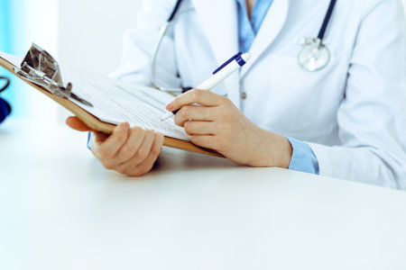 Female doctor using medical form on clipboard closeup. Physicianat work in hospital or clinic. Healthcare, insurance and medicine conceptの写真素材