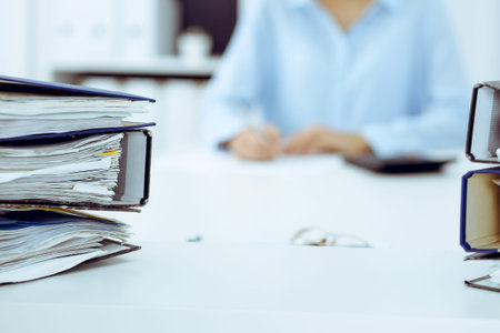 Binders with papers are waiting to be processed by business woman or bookkeeper back in blur. Internal Audit and tax conceptの写真素材