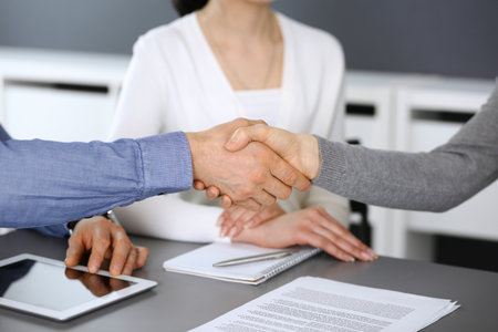 Group of business people shaking hands after discussing questions at meeting in modern office. Handshake close-up. Teamwork, partnership and agreement in business conceptの写真素材
