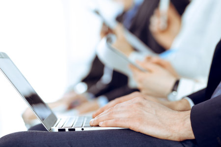 Business people working at meeting or conference, close-up of hands. Group of unknown businessmen and women in modern white office. Teamwork or coaching concept.の写真素材