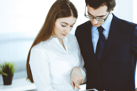 Businessmen and woman using tablet computer in modern office. Colleagues or company managers at workplace. Partners discussing contract. Business conceptの写真素材
