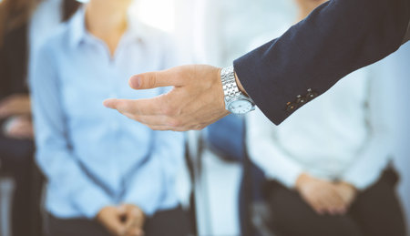 Business man making presentation to group of people in sunny office. Speaker delivering a seminar to his colleagues or business training. Teamwork and coaching concept.の写真素材
