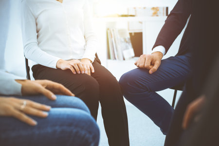 Group of people sitting in a circle during therapy in sunny office. Meeting of business team participating in trainingの写真素材