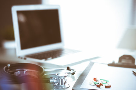 Stethoscope, prescription medical form lying on glass table with laptop computer. Medicine or pharmacy concept. Medical tools at doctor working table.の写真素材