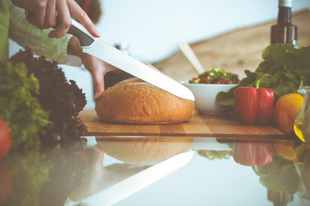 Unknown human hands cooking in kitchen. Woman slicing bread. Healthy meal, and vegetarian food conceptの写真素材