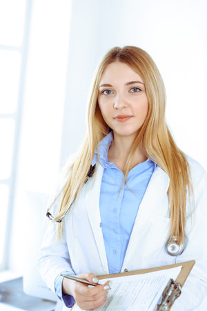 Young woman doctor at work in hospital office. Blue color blouse of therapist looks good. Medicine and healthcare conceptの写真素材