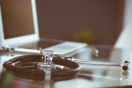Stethoscope, prescription medical form lying on glass table with laptop computer. Medicine or pharmacy concept. Medical tools at doctor working tableの写真素材