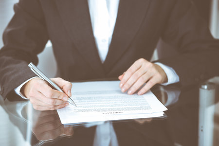 Unknown female hands with pen over document of contract. Agreement signing or business concept.の写真素材