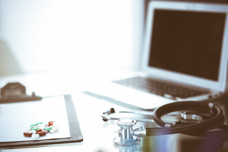 Stethoscope, prescription medical form lying on glass table with laptop computer. Medicine or pharmacy concept. Medical tools at doctor working tableの写真素材