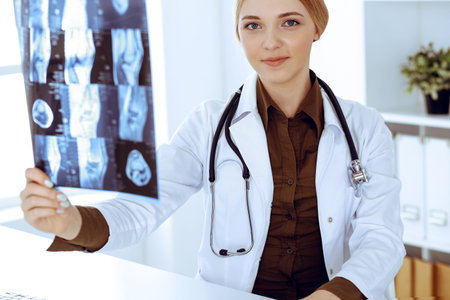 Doctor woman examining x-ray picture near window in hospital. Surgeon or orthopedist at work....