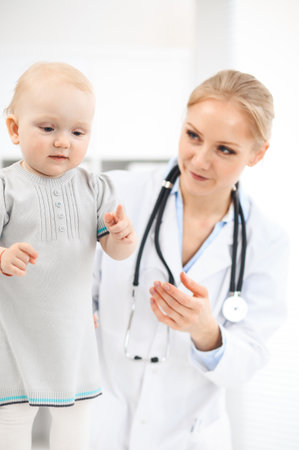 Doctor and patient in hospital. Little girl dressed in grey dress is being examined by doctor with stethoscope. Medicine conceptの写真素材