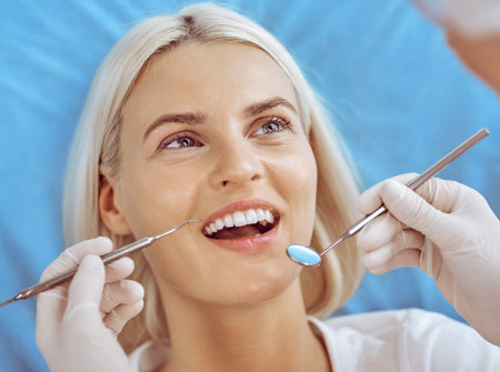 Smiling blonde woman examined by dentist at dental clinic. Healthy teeth and medicine conceptの写真素材