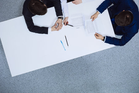 Group of business people and lawyer discussing contract papers sitting at the table, view from...
