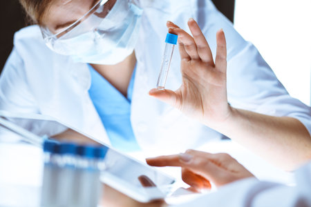 Coronavirus pandemic. Professional female scientist in protective eyeglasses researching tube with reagents in laboratory. Concepts of medicine and virus protectionの写真素材