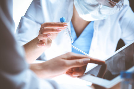 Coronavirus pandemic. Professional female scientist in protective eyeglasses researching tube with...