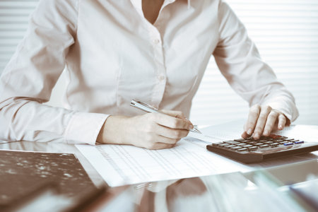 Bookkeeper woman or financial inspector making report, calculating or checking balance, close-up. Business, audit or tax conceptsの写真素材