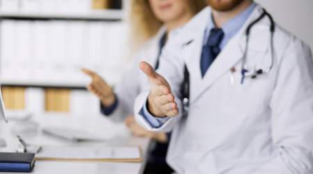 Two doctors sitting and offering helping hand for shaking hand or saving life. Medical help, countering viral infection and medicine conceptの写真素材