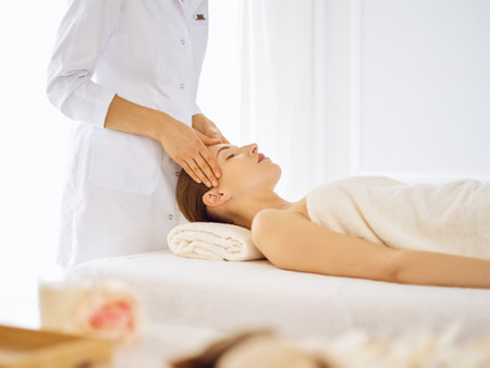 Beautiful woman enjoying facial massage with closed eyes. Spa treatment concept in medicine.の写真素材