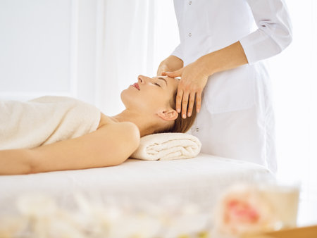 Beautiful woman enjoying facial massage with closed eyes. Spa treatment concept in medicine.の写真素材