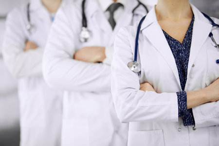 Doctors standing as a team with arms crossed in clinic. Medical help, insurance and medicine concept.の写真素材