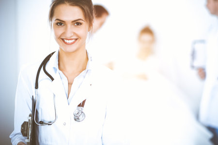 Female doctor smiling on the background with patient in the bed and two doctorsの写真素材