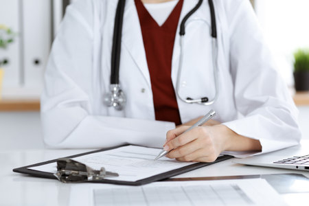 Unknown woman-doctor filling up an application form at working place. Medicine conceptの写真素材