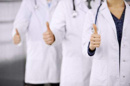Doctors standing as a team with thumbs up in clinic and ready to help patients. Medical help, insurance and medicine concept.の写真素材