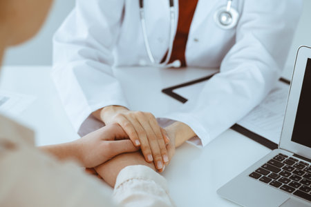 Hands of unknown woman-doctor reassuring her female patient, close-up. Medicine conceptの写真素材