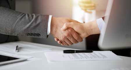 Business people shaking hands finishing contract signing in sunny office, close-up. Handshake and marketingの写真素材
