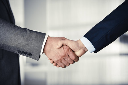 Business people in office suits standing and shaking hands, close-up. Business communication concept. Handshake and marketingの写真素材