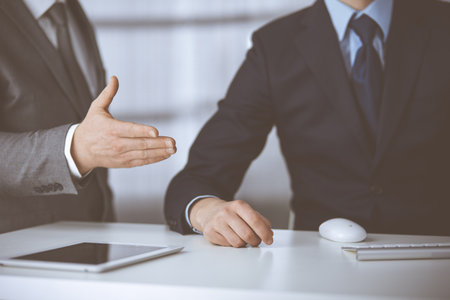 Business people using computer while working together in modern office. Unknown businessman or male entrepreneur with colleague at workplace. Teamwork and partnership conceptの写真素材