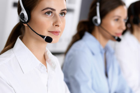 Call center. Group of operators at work. Focus on beautiful business woman in headset