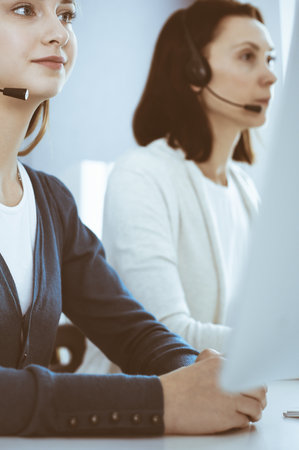 Call center. Group of operators at work. Focus on beautiful woman receptionist in headset at customer service office. Business conceptの写真素材