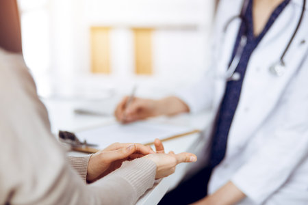 Doctor and patient discussing current health examination while sitting in sunny clinic. Medicine conceptの写真素材