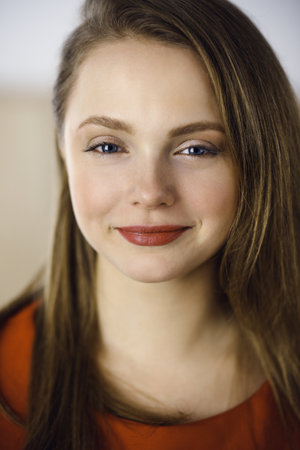 Head shot of a smart confident smiling millennial european woman standing with folded arms at home. Attractive young teenager student girl freelancer looking at camera, dressed in redの写真素材