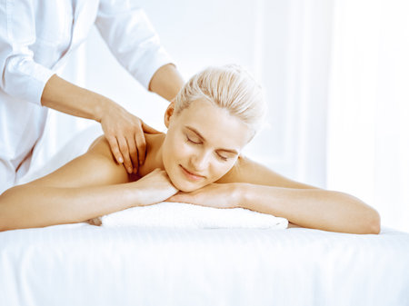 Beautiful blonde woman enjoying back massage in spa center. Beauty and lifestyleの写真素材