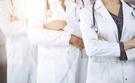 Doctors standing as a team with arms crossed in sunny clinic. Medical help, insurance and medicine conceptの写真素材