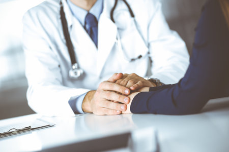 Unknown man-doctor reassuring his female patient, close-up. Two physicians consulting and giving some advices to woman. Perfect medical service, empathy in medicine during Coronavirus pandemic. Covid 2019.の写真素材