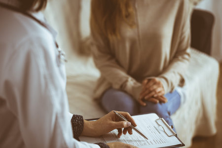 Unknown woman-doctor and patient discussing current health examination while sitting indoors. Stay at home concept during Coronavirus pandemic and self isolation quarantineの写真素材