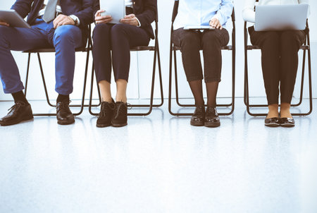 Group of business people sitting in office and waiting for job interview while using gadgets, close-up. Recruiting and headhunting conceptsの写真素材