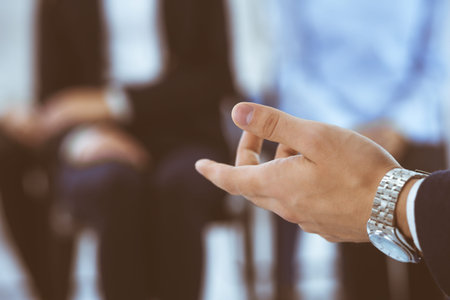 Businessman making presentation to group of people in office. Speaker delivering a seminar to his colleagues or business training. Teamwork and coaching concepts in businessの写真素材