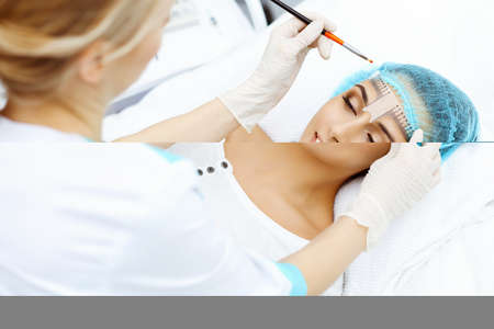 Professional beautician is going to correct eyebrow line at woman face using cosmetic ruler....