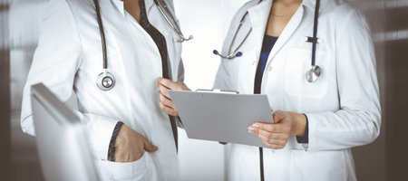 Two female physicians are discussing their patients medical tests, while standing in a clinic...