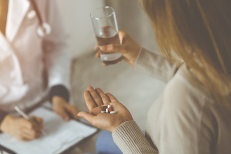 Close-up woman-patient holding pills near her doctor, time to take medications for headache.の写真素材