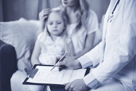 Doctor and patient. Pediatrician using clipboard while examining little girl with her mother at home. Sick and unhappy child at medical exam. Medicine conceptの写真素材