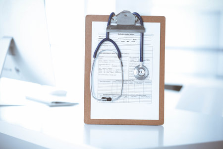 Stethoscope and clipboard with medication history records are on the table at the doctors working place. Medicine and health care conceptの写真素材
