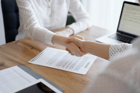 Business people shaking hands above contract papers just signed on the wooden table, close up. Lawyers at meeting. Teamwork, partnership, success conceptの写真素材
