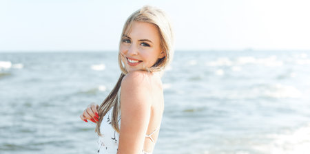 Happy blonde woman in free happiness bliss on ocean beach standing straight and posingの写真素材