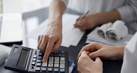 Woman accountant using a calculator and laptop computer while counting taxes for a client. Business...